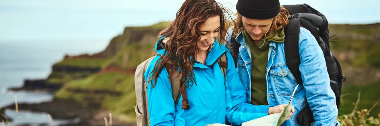 Two young travellers looking at a map on a hike in Ireland.