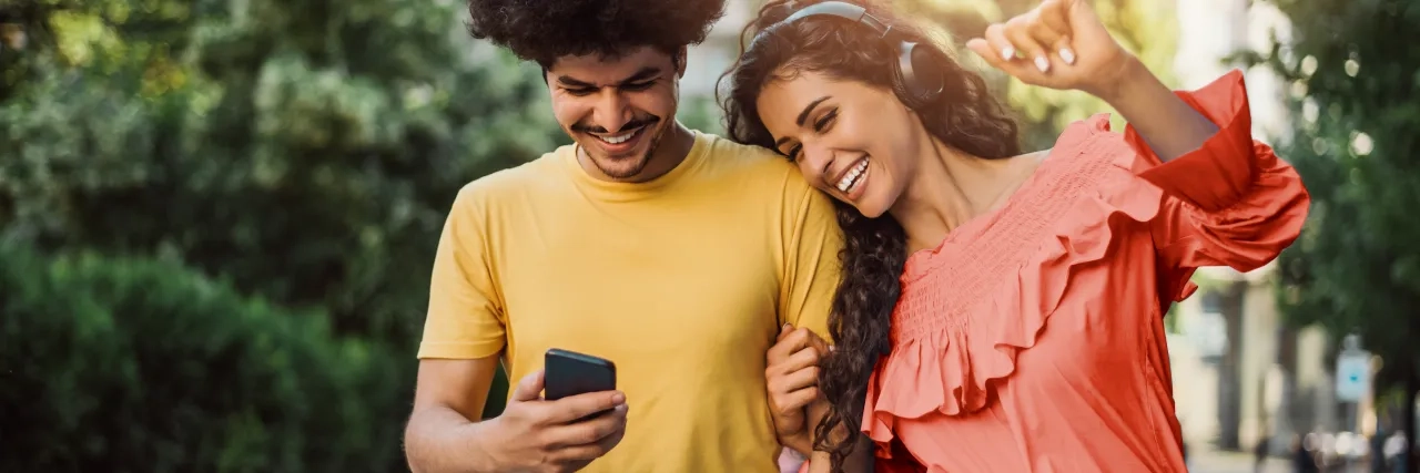 A man and woman walking together looking at a phone