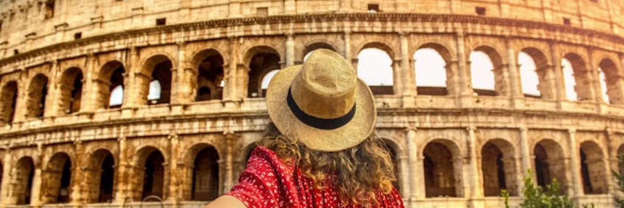 Woman dressed in red outside the Colosseum in Rome, Italy  