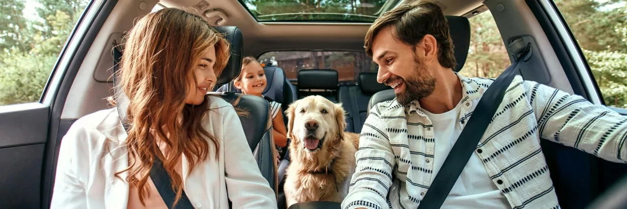 family in a car with their dog