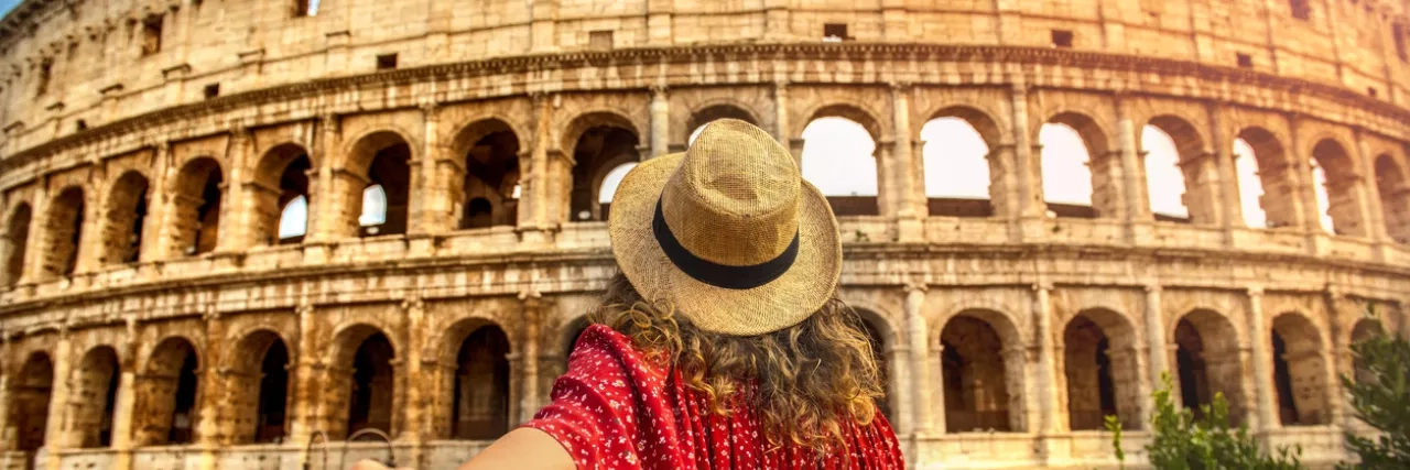 Woman dressed in red outside the Colosseum in Rome, Italy  