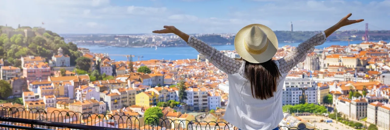 A happy tourist woman overlooks the colorful old town Alfama of Lisbon city