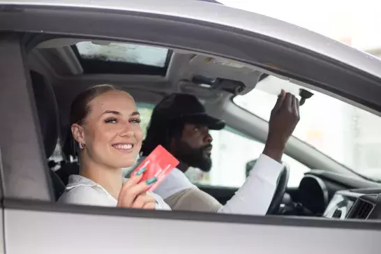 a couple in a car together. women holding up her CAA Everyday Membership card