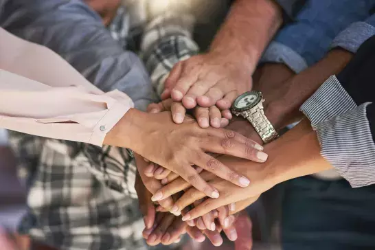 A group of people piling thier hands together 