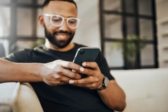 Man sitting on beige couch using mobile phone