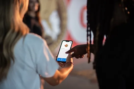 man pointing at caa app offer on a phone that a woman is holding