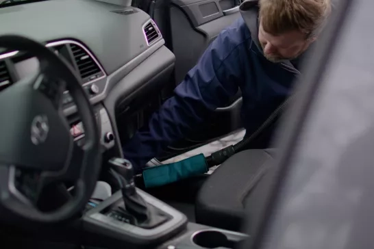 technician is detailing the interior of a vehicle