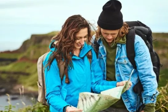 Couple look at map on cliffside vacation