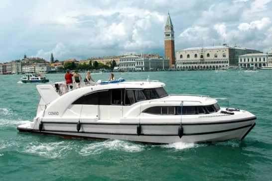 A group of friends enjoying a leisurely boat ride along the historic canals of Venice, with iconic architecture in the background