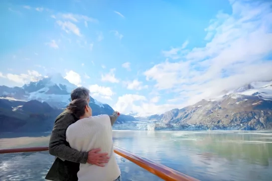A couple admiring glacier views on their Holland America Line cruise through Alaska.