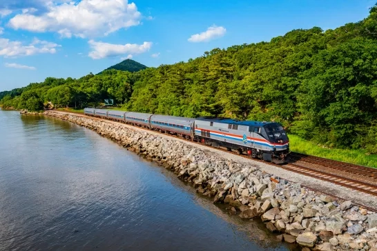 Amtrak Vacations train riding along the water and tree line