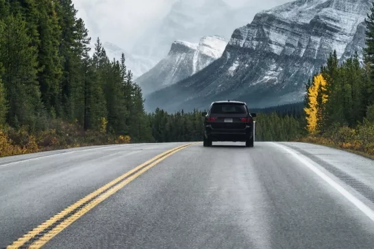 Car driving along the road with trees and mountains in the distance