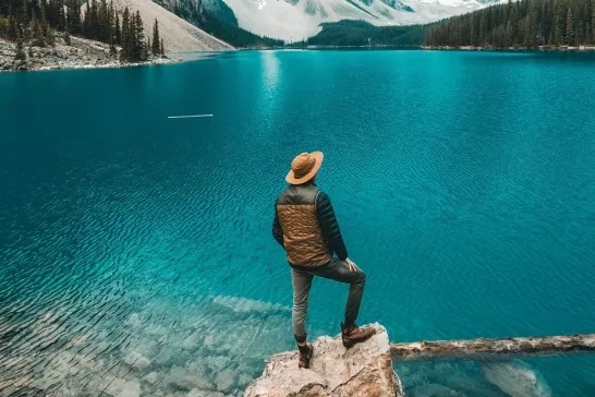 Man hiking in Canada standing on a rock overlooking a lake