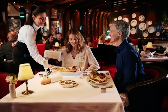 Stewardess serving a couple on Holland America Line