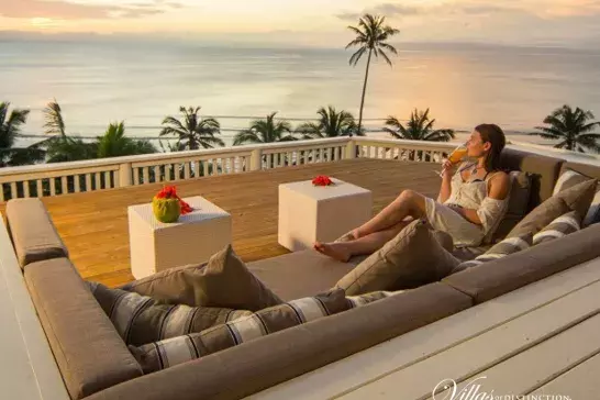 Woman lounging on her balcony watching the sunset in Fiji.