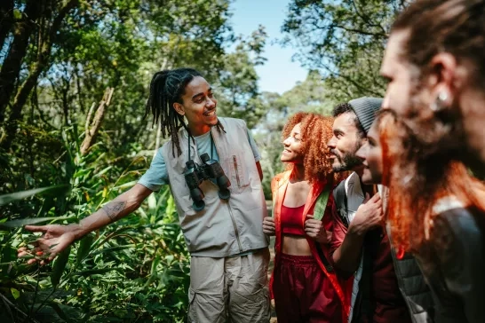 Tourist guide showing plants to a group of friends in the forest