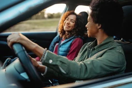 Two women driving in a car on the road