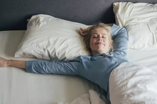 Woman laying in a hotel bed wearing pjs