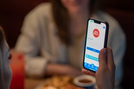 Woman using the CAA Mobile App at Swiss Chalet