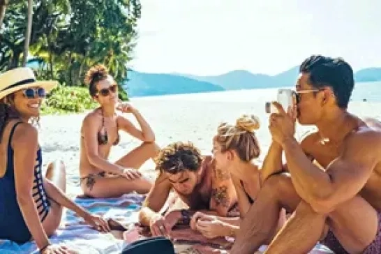 A group of friends enjoys a sunny day on a pristine beach, surrounded by crystal-clear waters and palm trees.