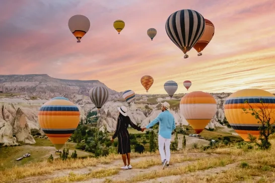 A couple watching the hot air balloons in Cappadocia, Turkey during sunrise