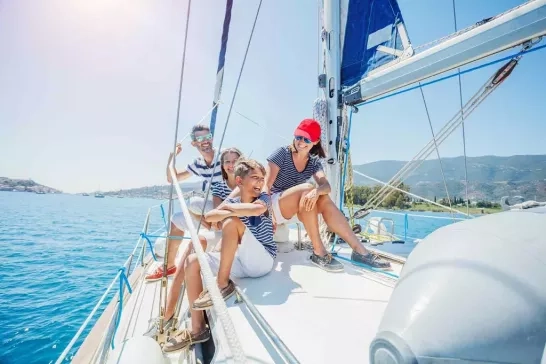 A joyful family on a sailing yacht, experiencing the thrill of sailing on clear blue waters under a bright sky