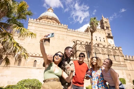 Friends take a joyful selfie in front of the iconic architecture of Sicily, capturing the fun of their trip.