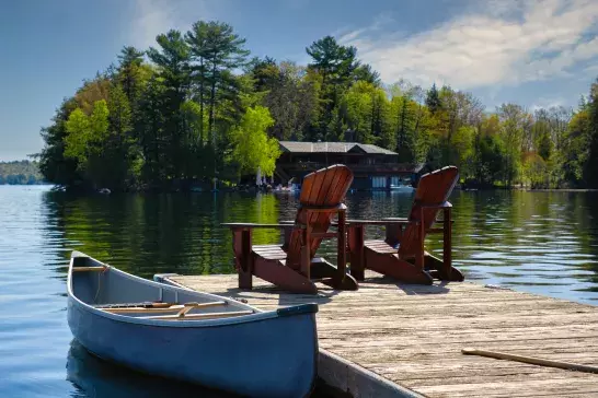 two-chairs-on-lakeside-dock-with-cottage