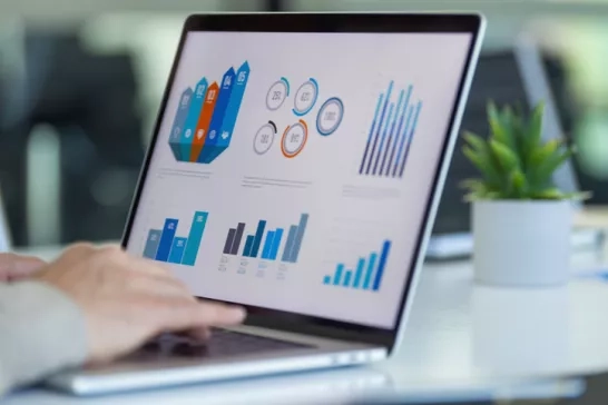 A laptop screen displaying various data charts and graphs representing business performance metrics.