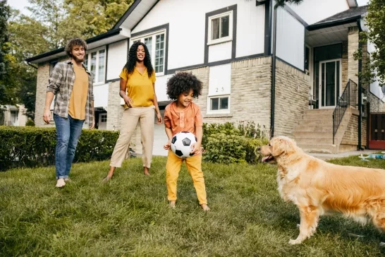 a young family playing with their dog in the backyard