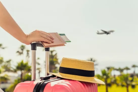 Traveler leaning on their wheely luggage