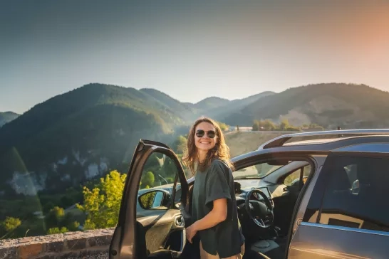 woman exiting car to view mountain