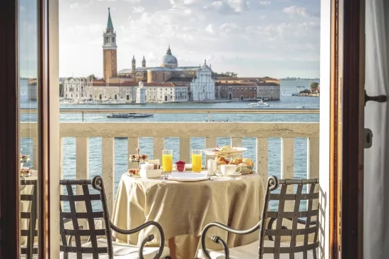 Breakfast setting for two on a waterfront balcony in Venice, Italy.