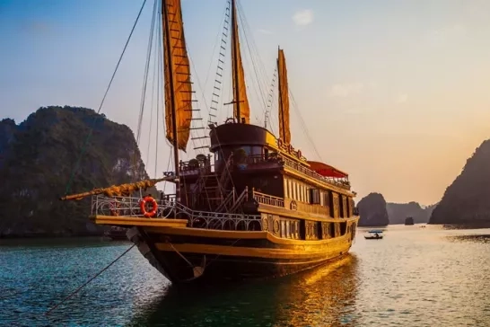 Viatnemese junk boat hotel during sunset in Halong Bay, Vietnam.