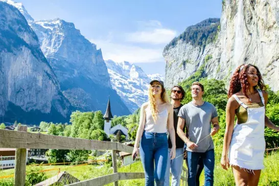 A group of friends enjoy a hike in the Swiss Alps, surrounded by towering mountains and picturesque valleys.