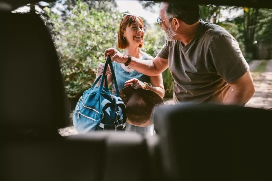 smiling-mature-couple-packing-luggage-in-car-trunk-for-weekend-getaway