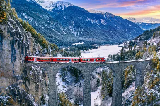 Aerial view of Train passing through famous mountain in Filisur, Switzerland. Landwasser Viaduct world heritage with train express in Swiss Alps snow winter scenery.