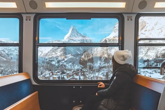 A woman looking outside of a train window directly at the Matterhorn in Zermatt, Switzerland