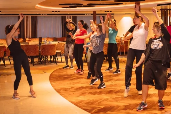 A group of travellers taking an AmaWaterways Zumba class with the wellness instructor onboard.