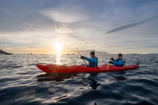Two people kayaking at sunset in Antarctica with Hurtigruten.