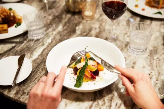 A traveller enjoying a beautifully plated meal on their Celebrity Cruise.