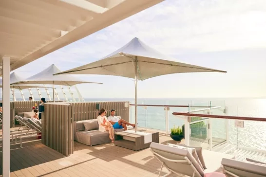 A couple sitting in a booth on the sundeck onboard a Celebrity Cruise ship.