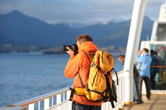 A photographer snapping a photo off the deck of a Hurtigruten cruise through Norway.