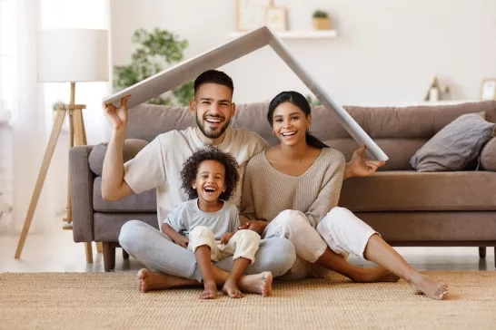 Happy family under fake cardboard roof in living room