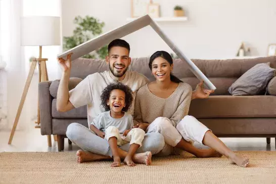 Happy family under fake cardboard roof in living room