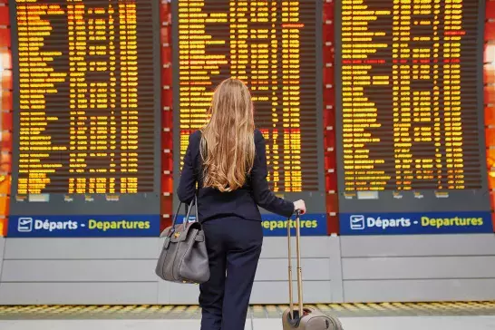  woman in international airport near large information display