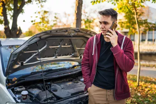 Oneadult man standing by his vehicle with open hood