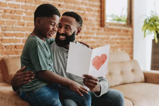 Son handing postcard to father on father's day