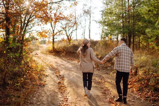 A couple enjoys a joyful moment together on a serene autumn day