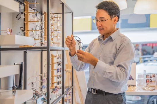 Man choosing new eyeglasses at optical store